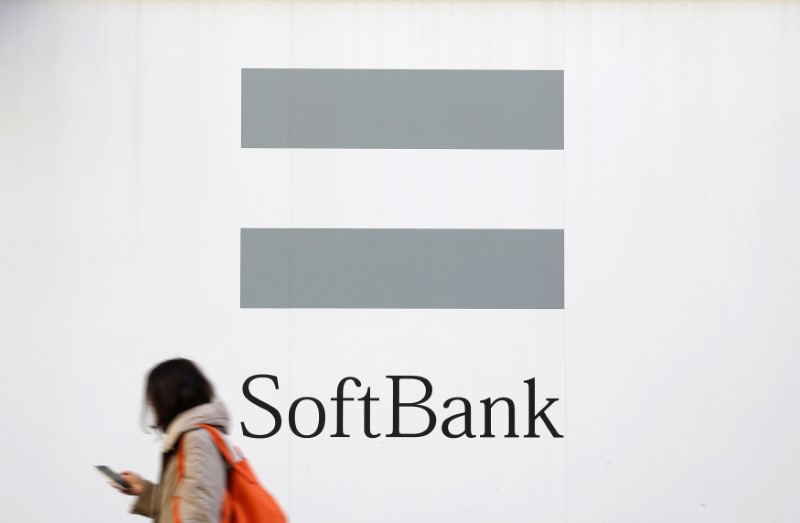 &copy; Reuters. FILE PHOTO: A woman using a mobile phone walks past the logo of SoftBank Corp in Tokyo