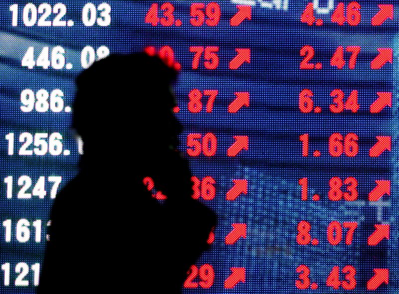 © Reuters. FILE PHOTO: Man is silhouetted against stock quotation board in Tokyo