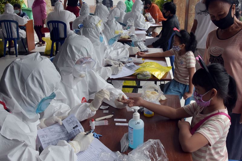 &copy; Reuters. Healthcare workers take blood sample from citizen for coronavirus disease (COVID-19) rapid test in Denpasar