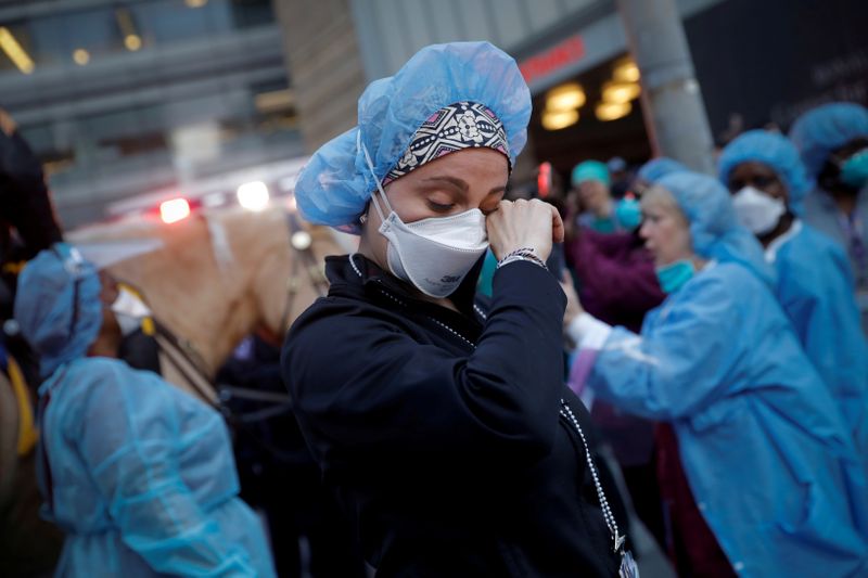 &copy; Reuters. FILE PHOTO: Nurse wipes away tears as NYPD polioce thank healthcare workers at NYU Langone Medical Center during outbreak of coronavirus disease (COVID-19) in New York