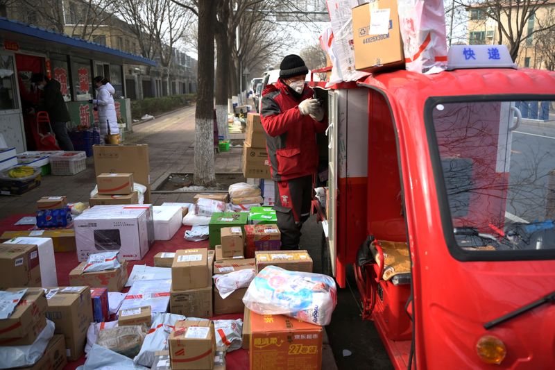 &copy; Reuters. FILE PHOTO: A JD.com delivery worker wearing a face mask unloads parcels outside a residential compound, as the country is hit by an outbreak of the novel coronavirus, in Beijing