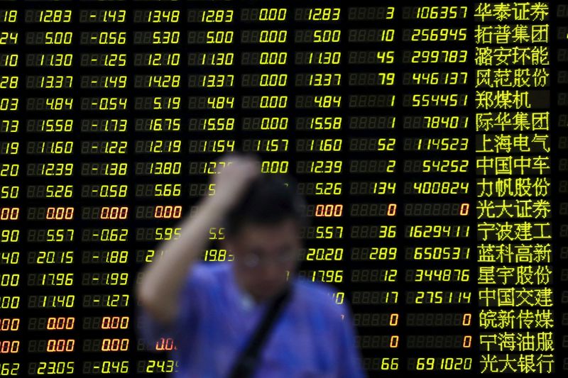 &copy; Reuters. FILE PHOTO: An investor stands in front of electronic board showing stock information at brokerage house in Shanghai
