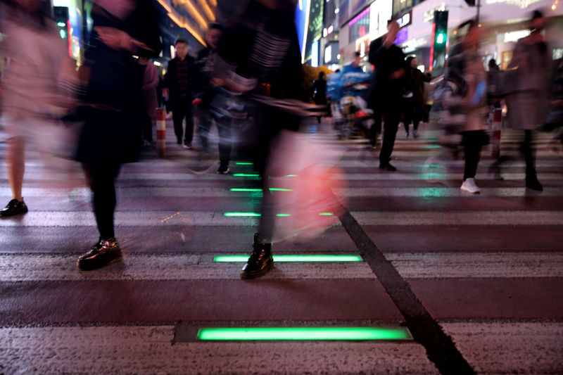 &copy; Reuters. People walk on a crossing with light signals for pedestrians near shopping malls in Shenyang