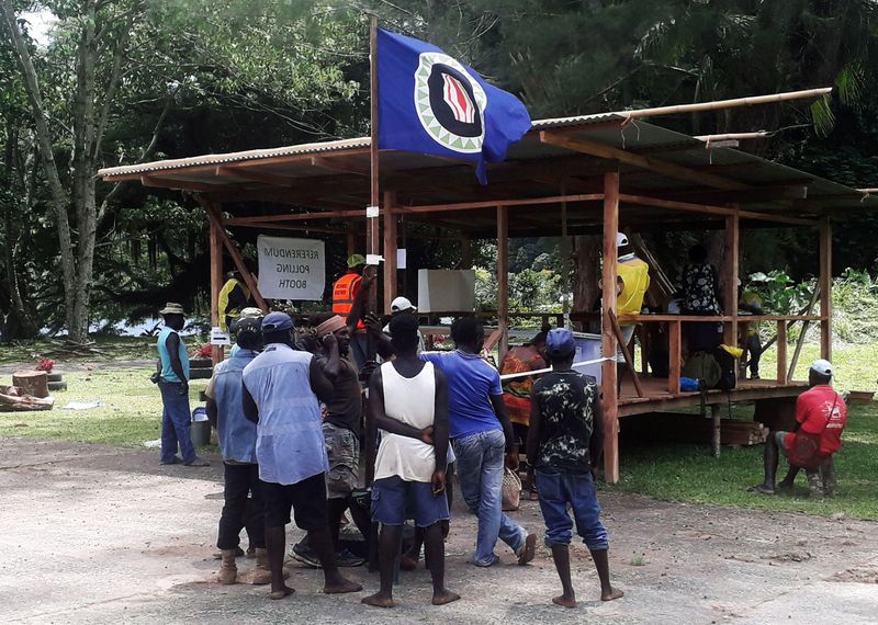 &copy; Reuters. FILE PHOTO: Residents hold a Bougainville flag at a polling station during a non-binding independence referendum in Arawa