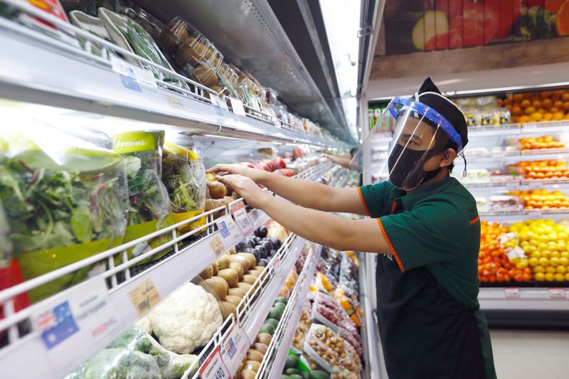 © Reuters. FILE PHOTO: A worker wearing a face shield and a protective face mask checks the vegetables at a Food Hall Supermarket amid the outbreak of the coronavirus disease (COVID-19), in Jakarta