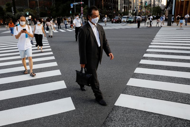 &copy; Reuters. People wearing protective masks make their way at a business district in Tokyo