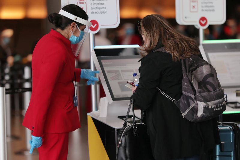 &copy; Reuters. An employee of the Avianca Airlines, wearing a face shield and a protective mask, talks to a passenger at the check-in section at the El Dorado International Airport, in Bogota