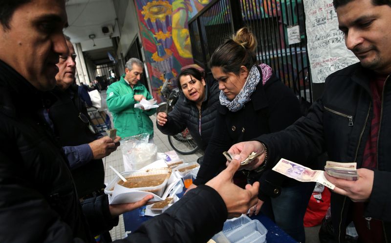 © Reuters. Workers who were fired from the Labor Ministry sell lentil soup outside the Ministry building in Buenos Aires