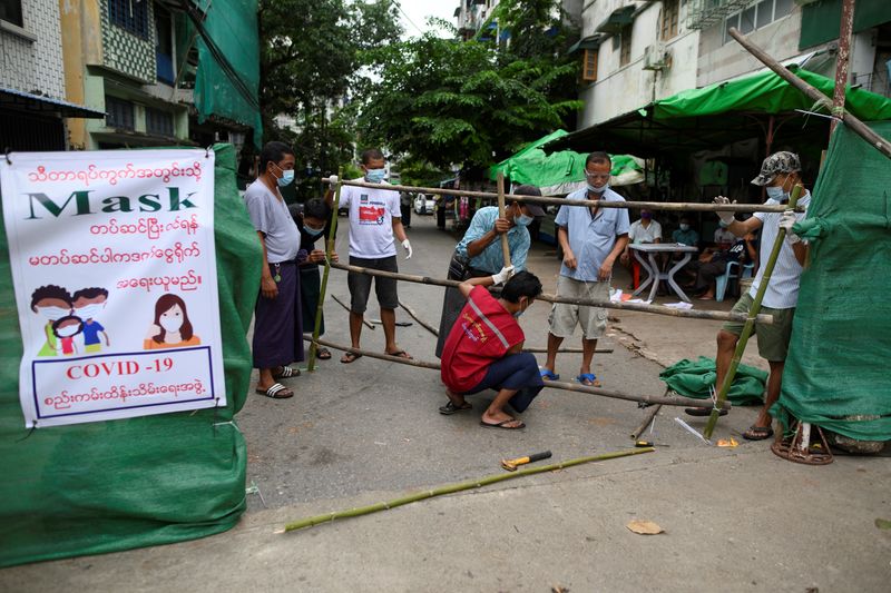 &copy; Reuters. FILE PHOTO: Men construct a barricade blocking off their street to prevent the spread of the coronavirus disease in Yangon