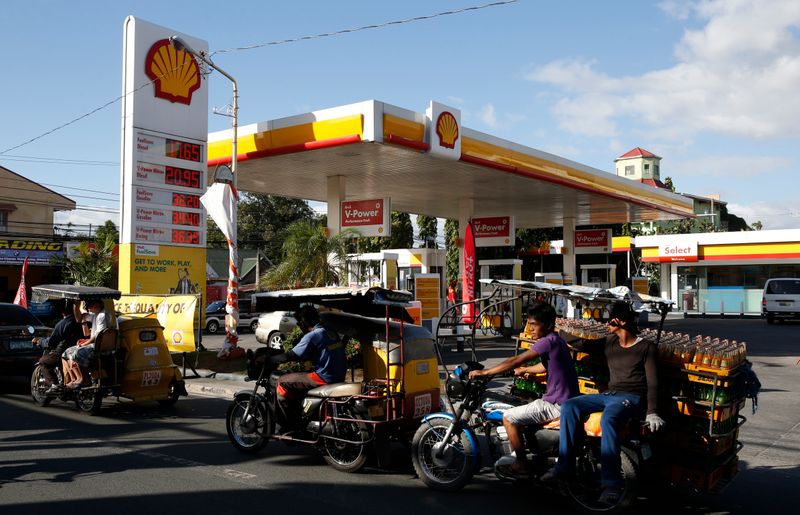 &copy; Reuters. FILE PHOTO: Residents transport commuters and soda bottles on tricycles past a Shell petrol station in Las Pinas