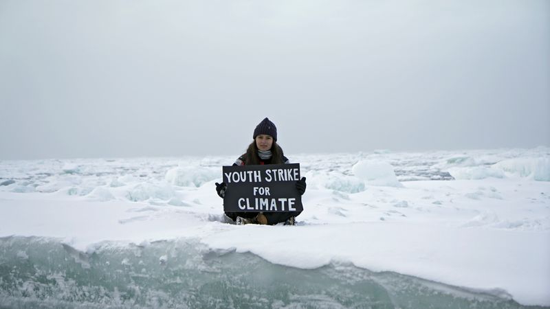 © Reuters. Environmental activist and campaigner Mya-Rose Craig holds a cardboard sign reading “youth strike for climate” in the middle of the Arctic Ocean