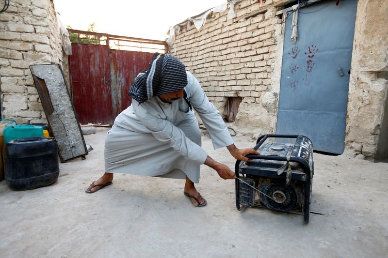 © Reuters. FILE PHOTO: A man activates his personal electrical generator at home during a series of power outages in Najaf, Iraq