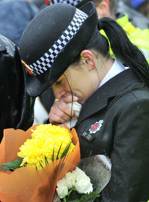 &copy; Reuters. A police officer bows her head during a vigil  in memory of Police officers Fiona Bone and Nicola Hughes, near the spot where they where shot and killed in Hattersley near Manchester