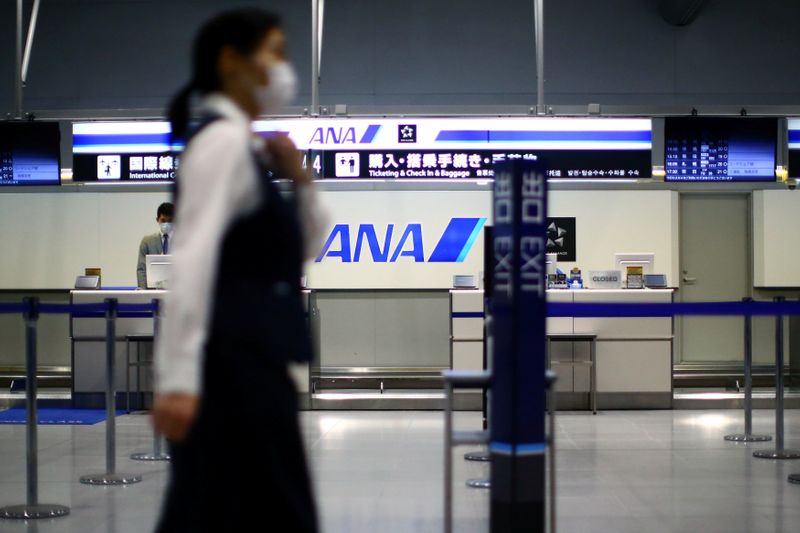 &copy; Reuters. An employee passes in front of an All Nippon Airways (ANA) counter at the almost empty Kansai International Airport in Osaka