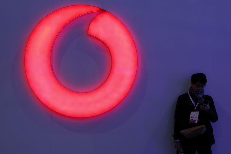 &copy; Reuters. A man checks his mobile phone next to a Vodafone logo at the Mobile World Congress in Barcelona