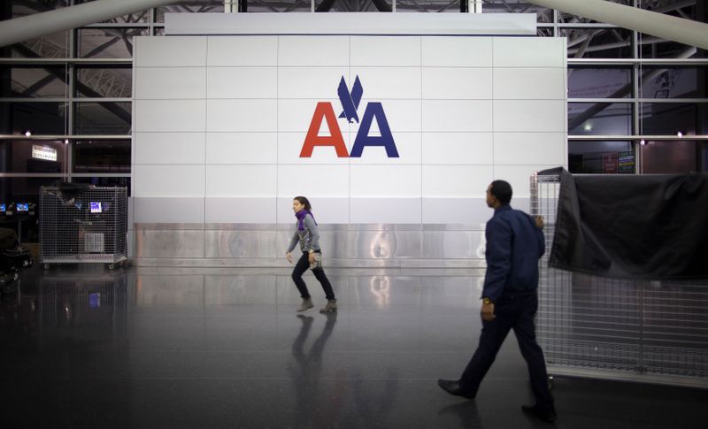 © Reuters. FILE PHOTO: People walk past an American Airlines logo at John F. Kennedy (JFK) airport in in New York