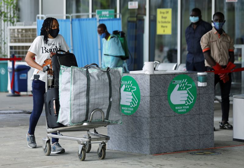 &copy; Reuters. FILE PHOTO: A passenger wearing a face mask pushes a trolley outside the Nnamdi Azikiwe International Airport in Abuja