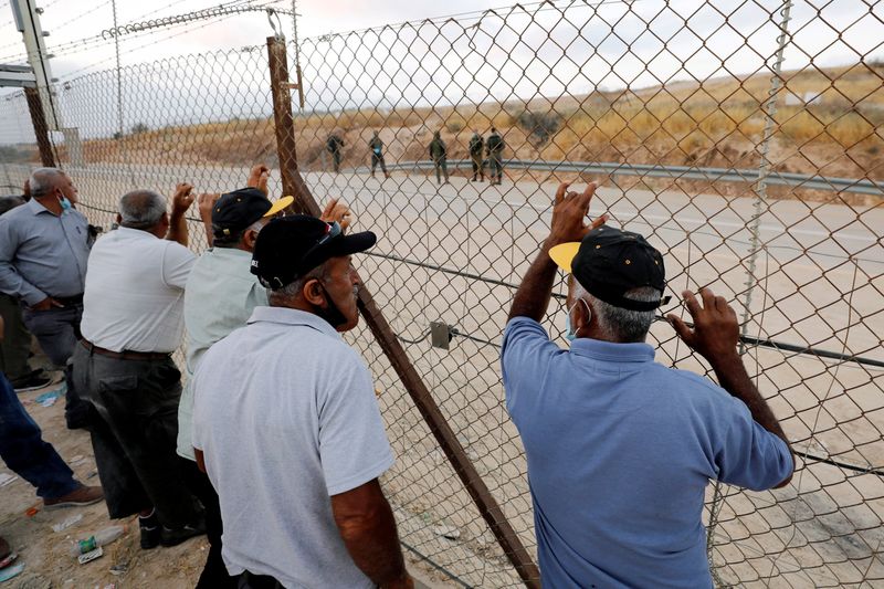 &copy; Reuters. FILE PHOTO: Palestinian laborers gather near an Israeli checkpoint closed amid fears of a second wave of COVID-19 infections, near Hebron