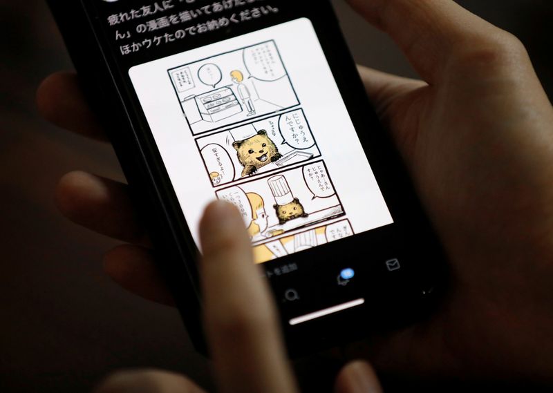 &copy; Reuters. Japanese manga artist Kamentotsu shows his his four-panel strip comic &apos;Koguma&apos;s Cake Shop&apos; on his smartphone at his workspace in Tokyo