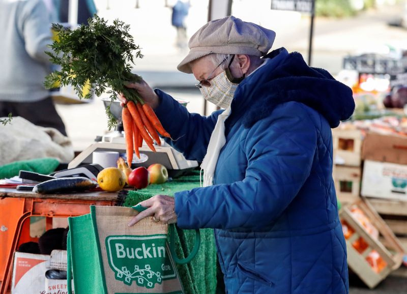 &copy; Reuters. A lady buys carrots from a market stall in Buckingham, Britain