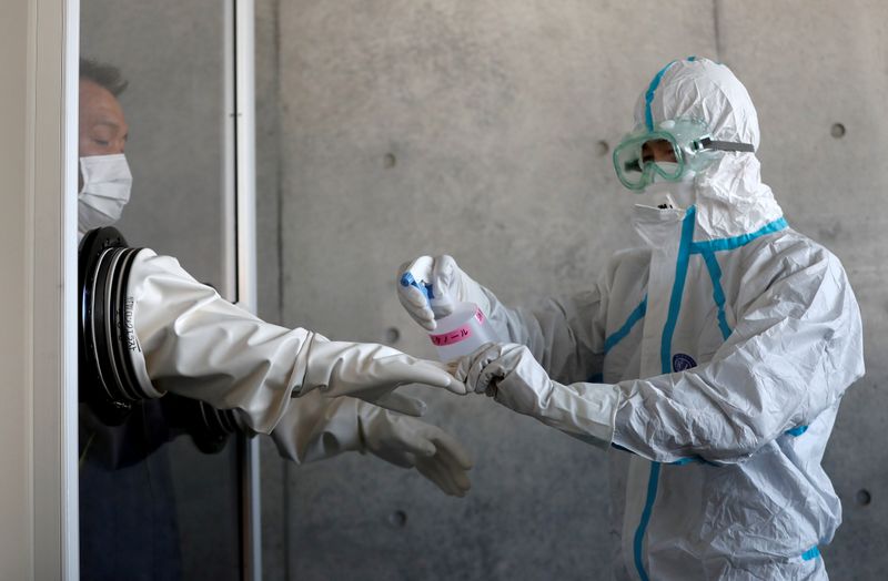 &copy; Reuters. Profissional de saúde desinfecta luvas de colega em Tosuka, ao sul de Tóquio