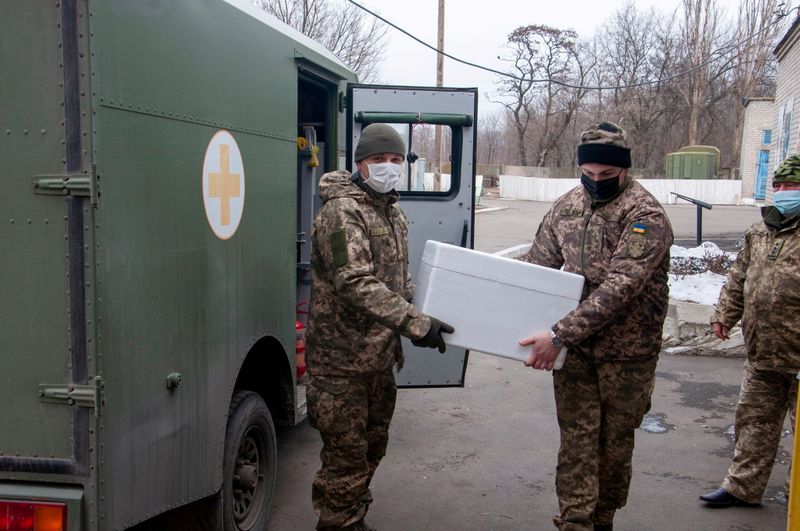 &copy; Reuters. FILE PHOTO: Ukrainian servicemen carry a box with the Oxford-AstraZeneca vaccine in Donetsk Region