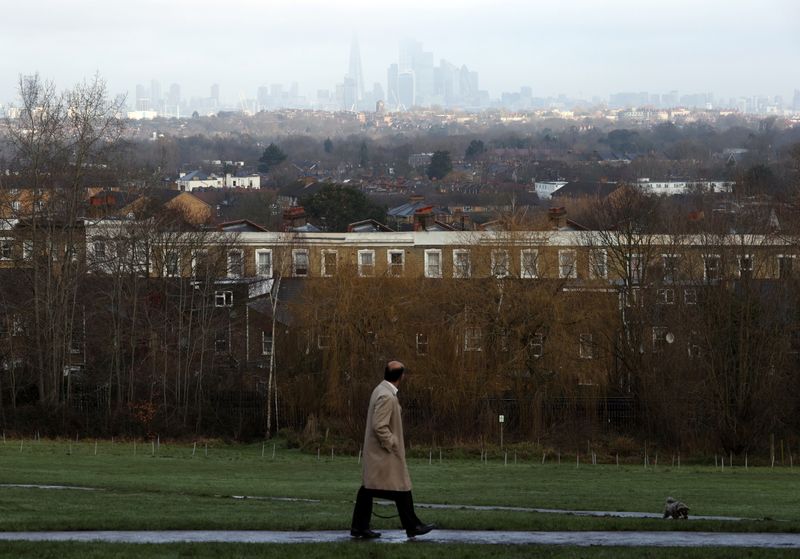 &copy; Reuters. A man looks towards the city of London financial district as he walks through a park in London