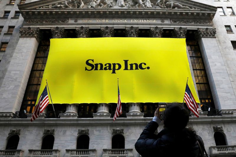 &copy; Reuters. A woman photographs a banner for Snap Inc. on the facade of the New York Stock Exchange