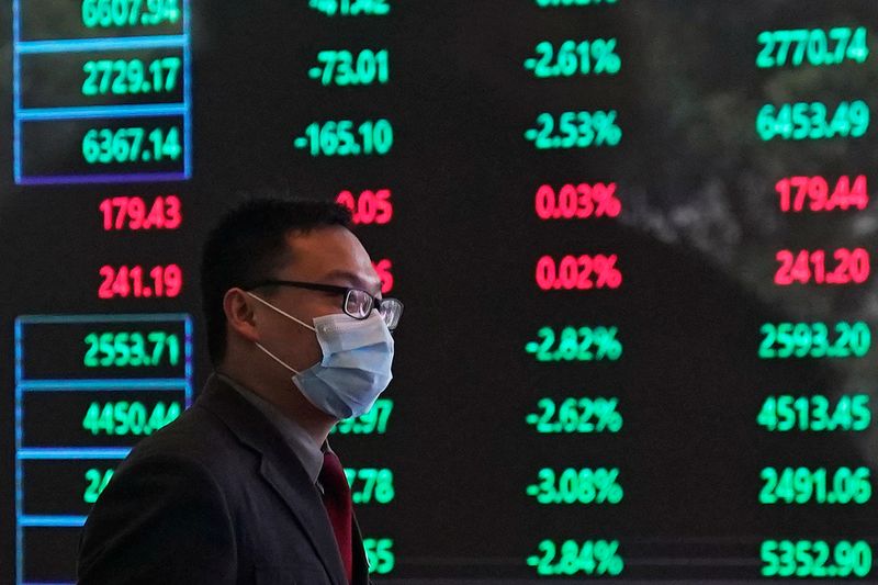 &copy; Reuters. Un uomo indossa una maschera protettiva all&apos;interno della Borsa di Shanghai, presso il distretto  finanziario di Pudong a Shanghai