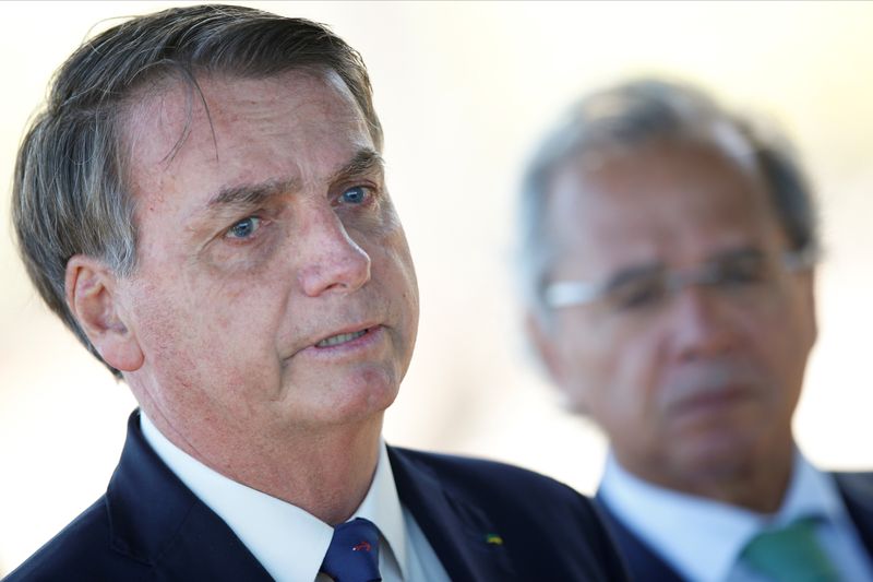 &copy; Reuters. O ministro da Economia, Paulo Guedes, observa o presidente da República, Jair Bolsonaro. 27/04/2020. REUTERS/Ueslei Marcelino.