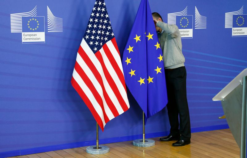 &copy; Reuters. Un uomo aggiusta la bandiera statunitense e la bandiera dell&apos;Unione europea presso la Commissione europea a Bruxelles