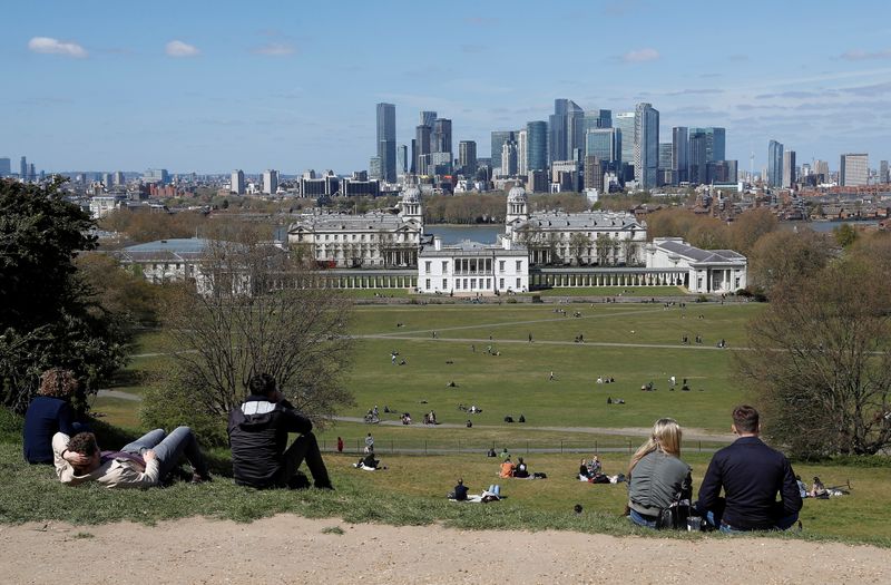 &copy; Reuters. FILE PHOTO: Visitors to Greenwich Park sit and look towards Canary Wharf financial district as lockdown restrictions are eased amidst the spread of the coronavirus disease (COVID-19) pandemic in London, Britain, April 25, 2021. REUTERS/Peter Nicholls