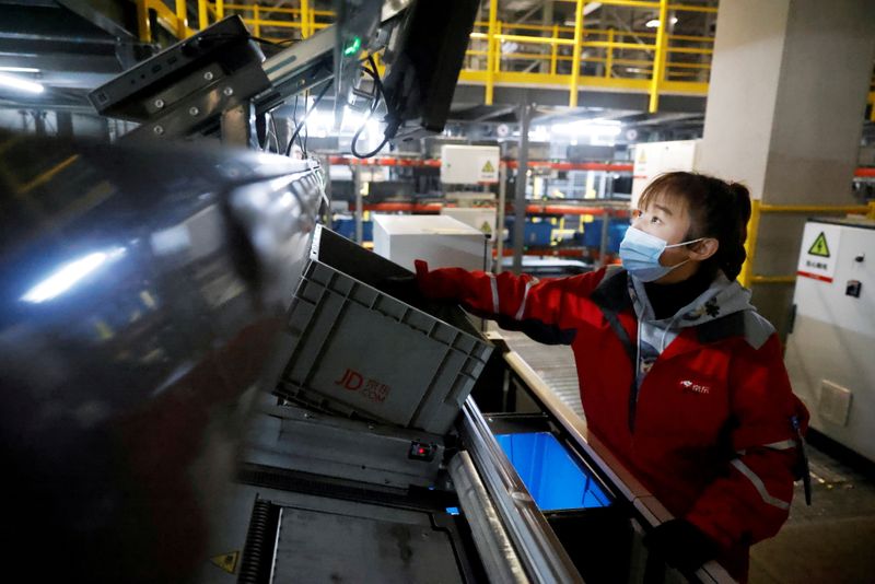 &copy; Reuters. FILE PHOTO: A staff member wearing a face mask works at JD.com's automated logistics center during a government organized tour on China's Singles Day shopping festival in Beijing, China November 11, 2020. REUTERS/Thomas Peter/File Photo