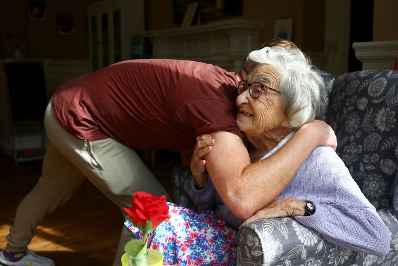 &copy; Reuters. Community coordinator Terence Surin hugs Joan Brock, 101, who is a resident at Alexander House Care Home in Wimbledon, as coronavirus disease (COVID-19) restrictions continue to ease, London, Britain, May 17, 2021. REUTERS/Hannah McKay