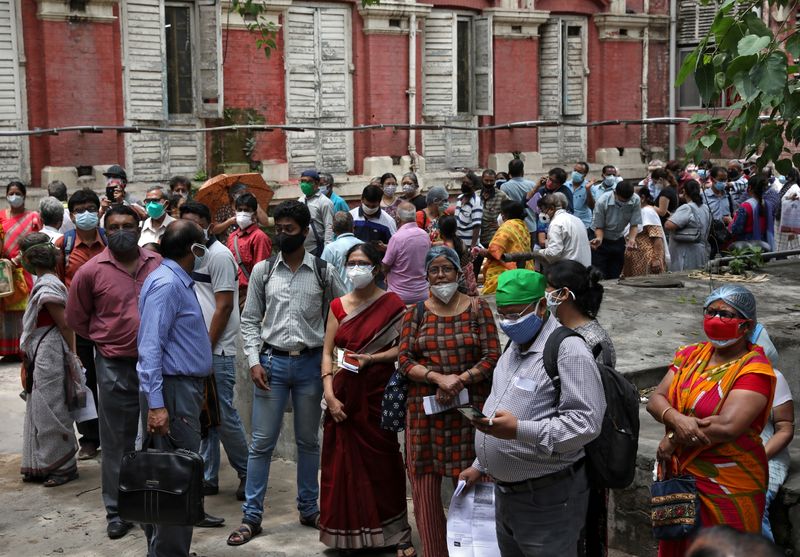 &copy; Reuters. FILE PHOTO: People wearing protective face masks wait to receive their second dose of COVISHIELD, a coronavirus disease (COVID-19) vaccine manufactured by Serum Institute of India, outside a vaccination centre in Kolkata, India, May 12, 2021. REUTERS/Rupa