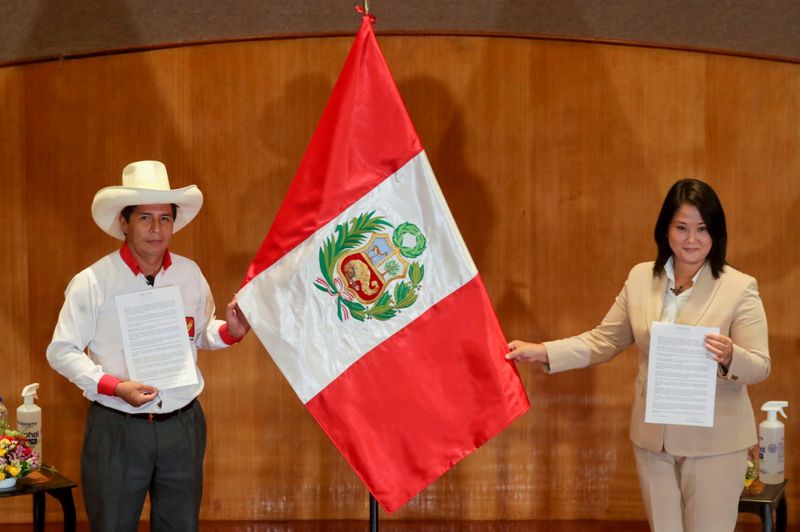 © Reuters. Peruvian presidential candidates Pedro Castillo and Keiko Fujimori, who will face each other in a run-off vote on June 6, hold Peru's national flag after signing a 