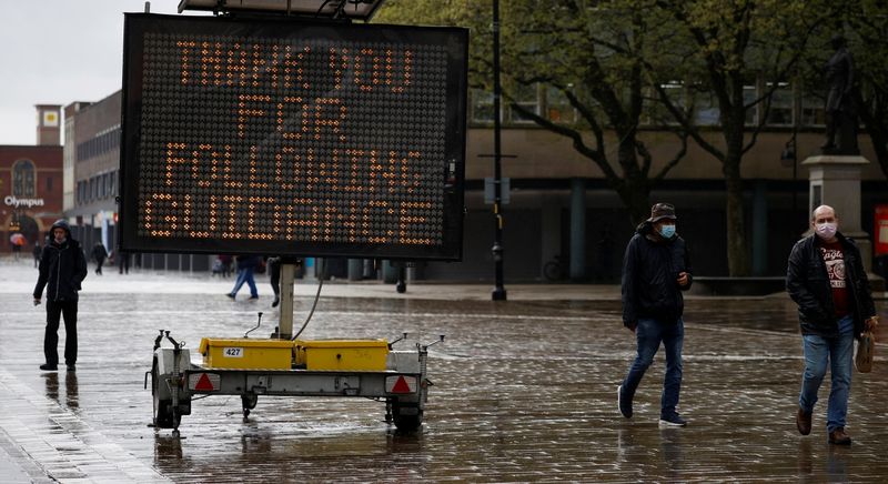 © Reuters. FILE PHOTO: People walk past an information sign, amid the outbreak of the coronavirus disease (COVID-19) in Bolton, Britain, May 17, 2021. REUTERS/Phil Noble