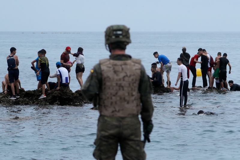 &copy; Reuters. جندي إسباني يقف أمام مهاجرين مغربيين بعد دخولهم جيب سبتة سباحة في صورة التقطت يوم الثلاثاء. 