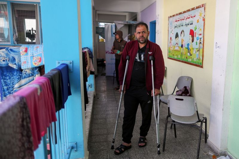 &copy; Reuters. الفلسطيني إيهاب العطار الذي يقول إن منزله دُمر في قصف أدى لمقتل أربعة من أفراد عائلته، يمشي مستندا الى عكازين في مدرسة تديرها الأمم المتحدة 