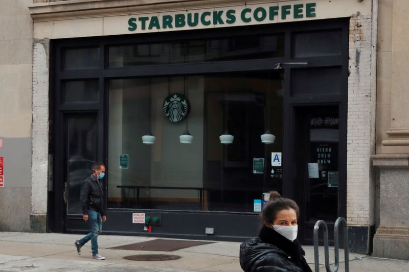 &copy; Reuters. FILE PHOTO: A man wearing a mask walks in front of a shuttered Starbucks as the spread of the coronavirus disease (COVID-19) outbreak continues in the Manhattan borough of New York City, U.S., April 27, 2020. REUTERS/Lucas Jackson  