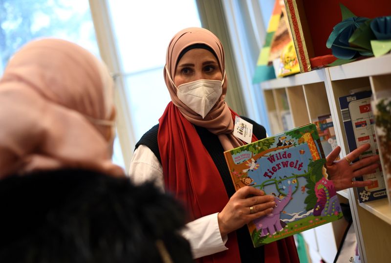 &copy; Reuters. Social worker Noor Zayed of the Stadtteilmuetter migrant integration project run by Protestant charity Diakonie speaks to Um Wajih, a Syrian mother of two children, in Berlin's district of Neukoelln, Germany May 4, 2021. REUTERS/Annegret Hilse