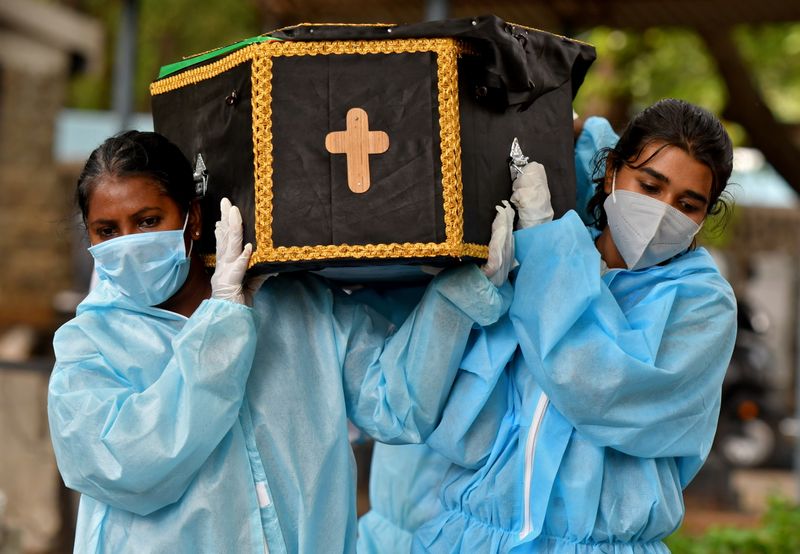 &copy; Reuters. Voluntários Akshaya (D), 22, e Esther Mary, 41, carregando um caixão com corpo de vítima de Covid-19 em Bengaluru, Índia
18/5/2021 REUTERS/Samuel Rajkumar