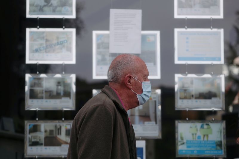 &copy; Reuters. FOTO DE ARCHIVO: Un hombre con mascarilla pasa frente al escaparate de una agencia inmobiliaria en Madrid