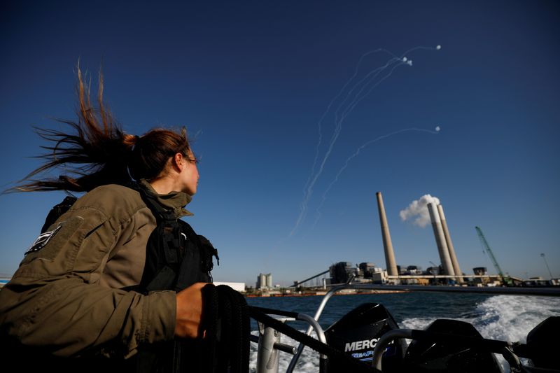 © Reuters. An Israeli soldier looks on as Israel's Iron Dome anti-missile system intercept rockets launched from the Gaza Strip towards Israel, as it seen from a naval boat patrolling the Mediterranean Sea off the southern Israeli coast as Israel-Gaza fighting rages on May 19, 2021 REUTERS/ Amir Cohen