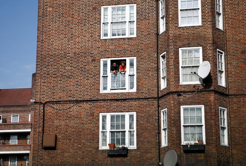 &copy; Reuters. FILE PHOTO: Men look out of an apartment window in Kennington as the spread of the coronavirus disease (COVID-19) continues, London, Britain, April 11, 2020. REUTERS/Henry Nicholls