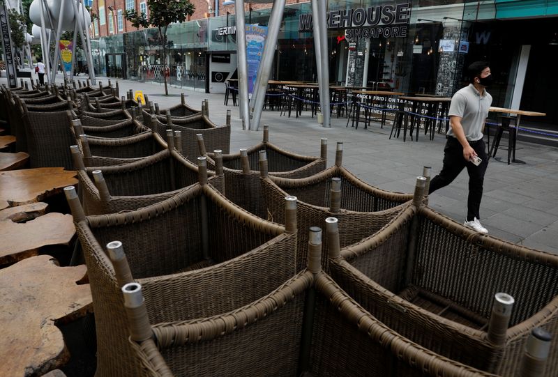 &copy; Reuters. FILE PHOTO: A man walks past chairs stacked up outside restaurants as dining-in is restricted to curb the coronavirus disease (COVID-19) outbreak in Singapore May 17, 2021.   REUTERS/Edgar Su