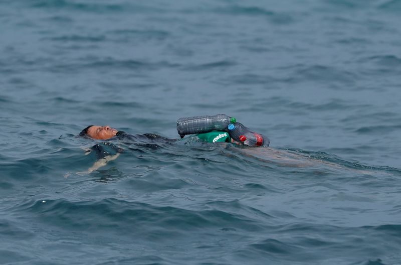 &copy; Reuters. A Moroccan boy swims using bottles as a float, near the fence between the Spanish-Moroccan border, after thousands of migrants swam across the border, in Ceuta, Spain, May 19, 2021. REUTERS/Jon Nazca/File photo    