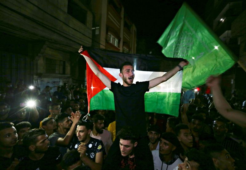 © Reuters. Cittadini palestinesi celebrano per strada il cessate il fuoco tra Israele e Hamas, nella striscia di Gaza meridionale. REUTERS/Ibraheem Abu Mustafa