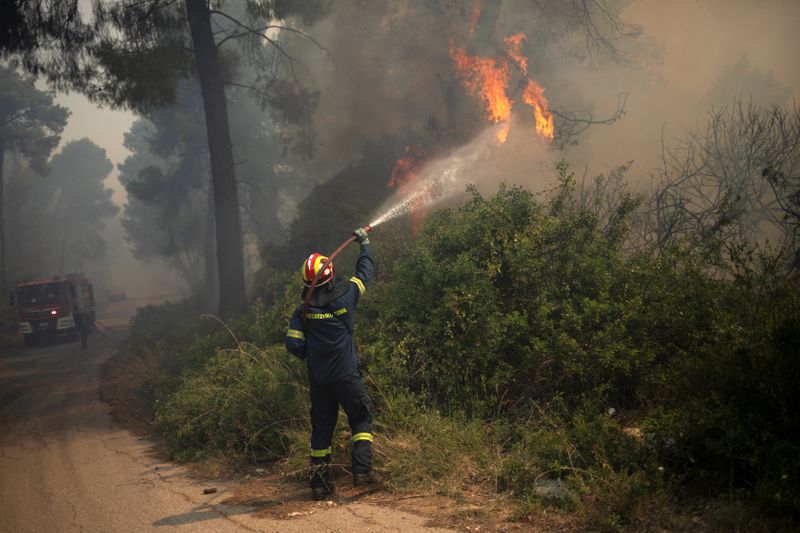 &copy; Reuters. FILE PHOTO: A firefighter tries to extinguish a fire burning in the village of Mazi, near Corinth, Greece, May 20, 2021. REUTERS/Stelios Misinas