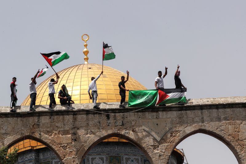© Reuters. Palestinians hold flags as they stand at the compound that houses Al-Aqsa Mosque, known to Muslims as Noble Sanctuary and to Jews as Temple Mount, in Jerusalem's Old City May 21, 2021. REUTERS/Ammar Awad